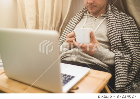Young man laying in bad with laptop and cup of tea 37224027