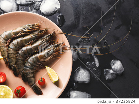 Raw shrimps with lemon on black background Raw shrimps with lemon on black background 37225924