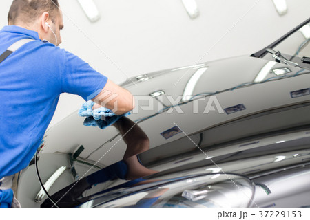 Man on a car wash polishing car with a polish machine Man on a car wash polishing car with a polish machine 37229153