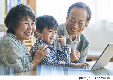 パソコンをする孫とそれを見るシニア 37229840