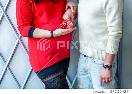 Pregnant couple holding shoes in hands Pregnant couple holding shoes in hands 37230427