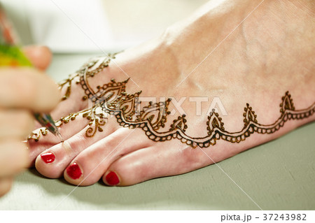 Mehendi. Master applying henna on model's leg 37243982