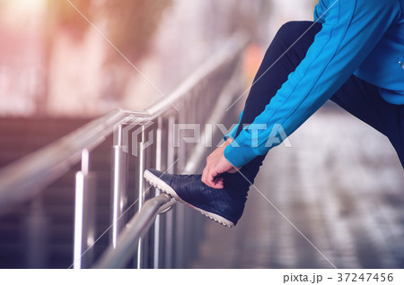 Closeup of unrecognized person tying shoe laces Closeup of unrecognized person tying shoe laces 37247456