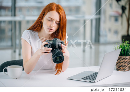 redhead girl photographer is viewing images on 37253824