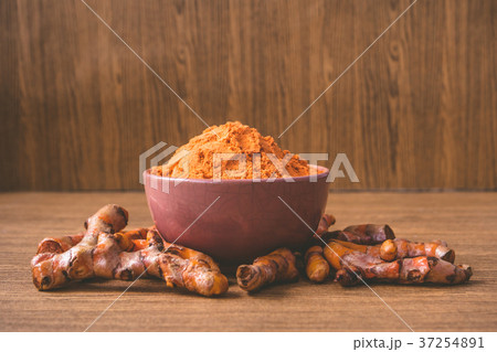 Turmeric roots with turmeric powder on wooden Turmeric roots with turmeric powder on wooden 37254891