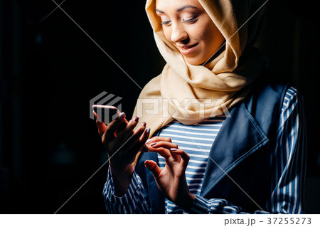 Muslim woman messaging on a mobile phone in cafe 37255273