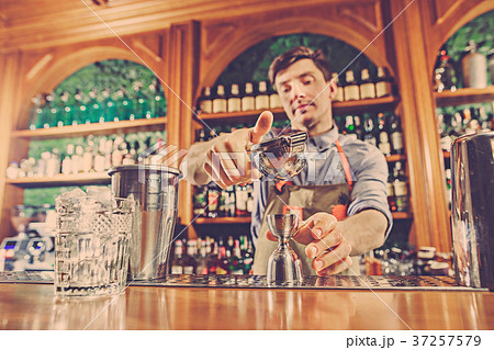 Expert barman is making cocktail at night club. Expert barman is making cocktail at night club. 37257579