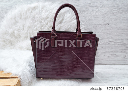 Dark purple bag on white fur. Fashionable concept Dark purple bag on white fur. Fashionable concept 37258703