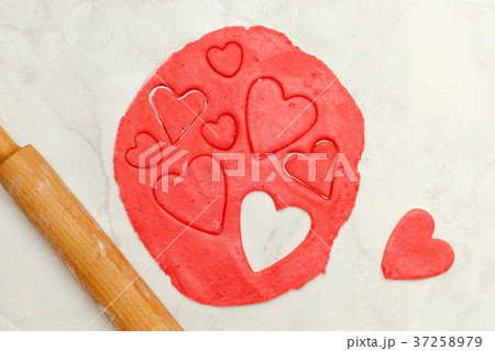 Red dough with a rolling pin and cut out hearts Red dough with a rolling pin and cut out hearts 37258979