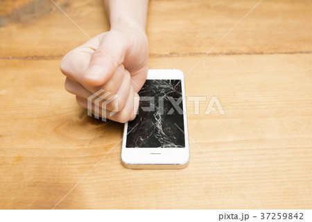 画面がひび割れたスマトフォンと女性の手 37259842