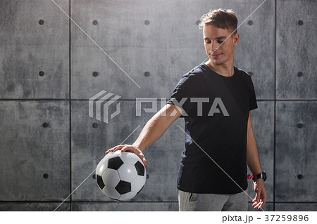 Young man holding soccer ball in hand 37259896