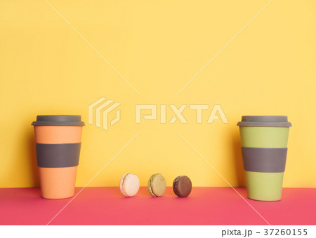 Cup of coffee to go with macaron on yellow and pink background Cup of coffee to go with macaron on yellow and pink background 37260155
