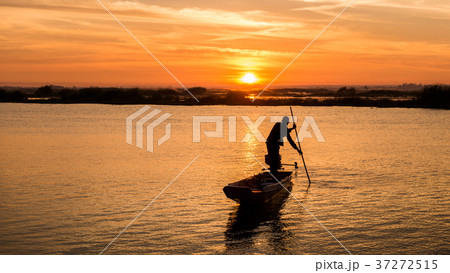 fisherman on long tail boat in the lake on sunrise fisherman on long tail boat in the lake on sunrise 37272515