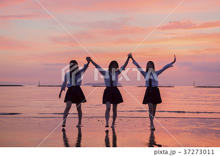 夕焼けの海と女子高生の写真素材