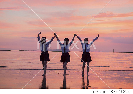 夕焼けの海と女子高生の写真素材