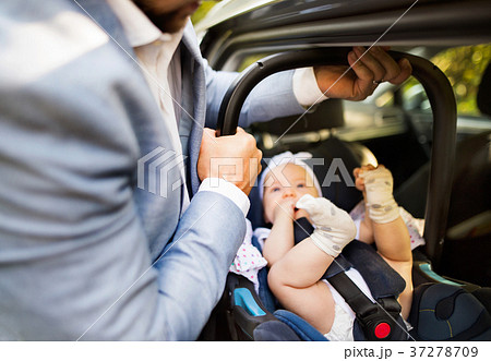 Unrecognizable man putting baby girl in the car. 37278709