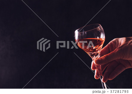Male hand holding a glass of wine on black  37281793