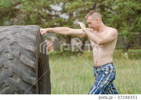 Young man boxing with the tire. Workout 37286351