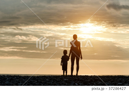 Mom and son are standing on the beach 37286427