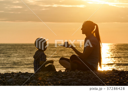 Mom and son are playing on the beach at sunset 37286428