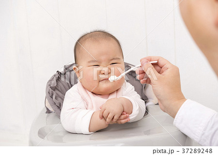 赤ちゃんに離乳食を食べさせる父親の写真素材