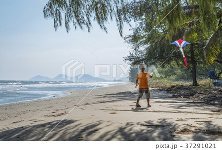 One Asian boy playing kite on a beach. One Asian boy playing kite on a beach. 37291021