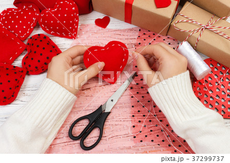 Woman creating red heart on wooden table. Woman creating red heart on wooden table. 37299737
