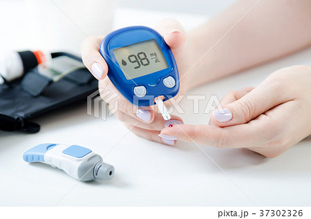 Woman checking blood sugar level by glucometer 37302326