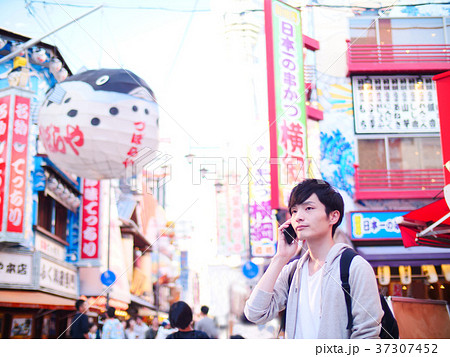 大阪観光 スマホで通話する一人旅の男性の写真素材