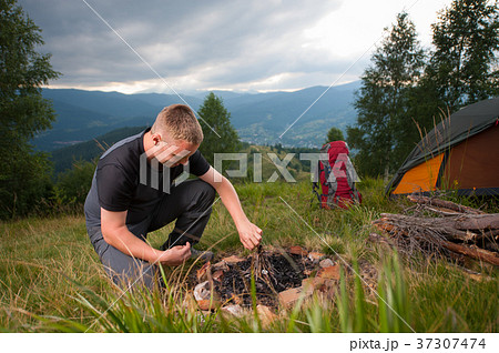 Young male hiker kindling firewood on the hill 37307474