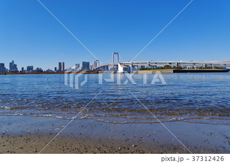 快晴の東京湾 波打ち際とレインボーブリッジ 18 01 A 2 広角 前ボケ大 引き波の写真素材