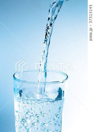 Pouring water from bottle into glass in blue light 37313143
