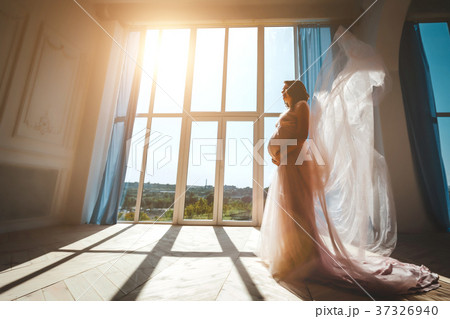 Young pretty pregnant model standing near window Young pretty pregnant model standing near window 37326940