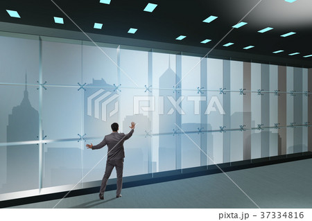 Businessman in front of office window thinking of 37334816