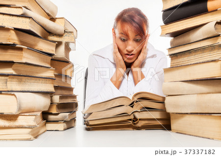 Woman sitting by the desk with pile of books 37337182