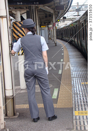 駆け込み乗車している乗客と発車メロディースイッチを切ろうとしている女性車掌さんの写真素材