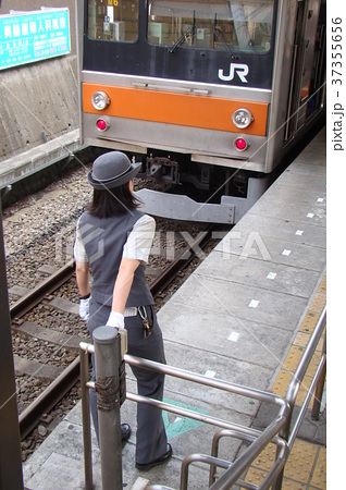 発車メロディースイッチに後ろ手をかける女性車掌さんの写真素材