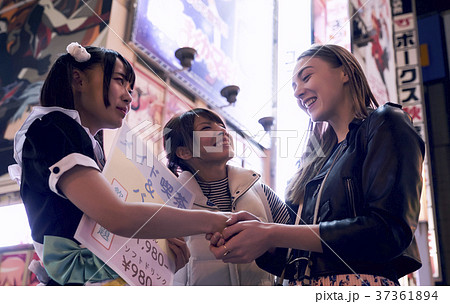 夜の秋葉原 メイドと握手する外国人女性の写真素材