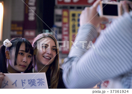 東京の夜 メイドと写真を撮る外国人女性の写真素材