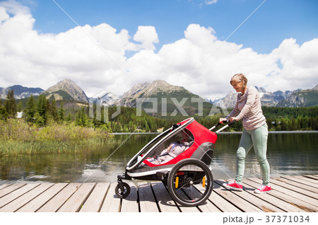 Senior woman and children in jogging stroller Senior woman and children in jogging stroller 37371034