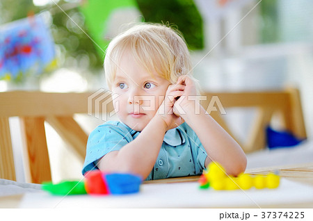Creative boy playing with colorful modeling clay at kindergarten 37374225