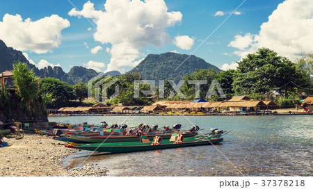 long tail boats on sunset at Song river, Vang Vien long tail boats on sunset at Song river, Vang Vien 37378218