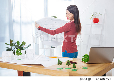 Cheerful engineer smiling while comparing two Cheerful engineer smiling while comparing two 37380751