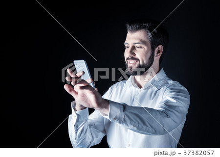 Joyful smart man looking at his smartphone screen Joyful smart man looking at his smartphone screen 37382057