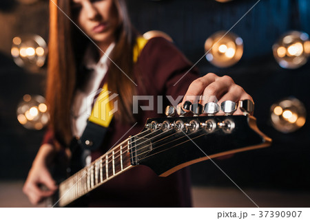 Female rock guitarist in suit tunes the guitar Female rock guitarist in suit tunes the guitar 37390907