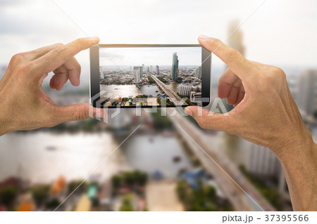 Hands holding smartphone taking photo of city 37395566