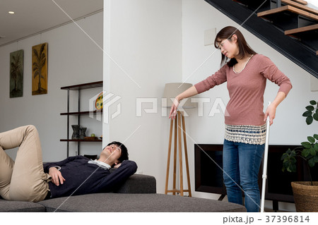 掃除を手伝う様訴える妊娠中の妻とゴロゴロする夫 37396814