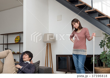 掃除を手伝う様訴える妊娠中の妻とゴロゴロする夫 37396818