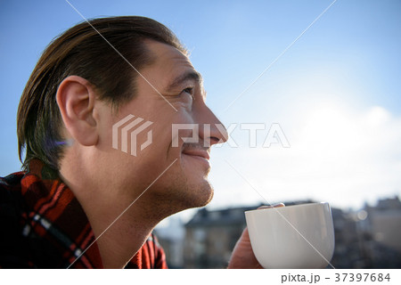 Cheerful man drinking coffee on terrace in the Cheerful man drinking coffee on terrace in the 37397684