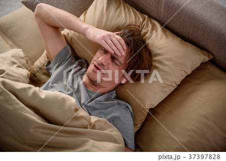 Exhausted guy suffering from a migraine in bedroom 37397828